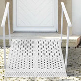 White metal ramp with handrails leading up to a door on a stone pathway.